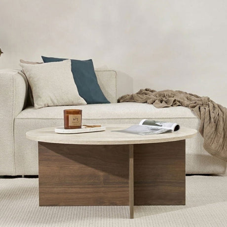Runder Couchtisch mit Travertinplatte und dunklem Holzsockel in Kreuzform.